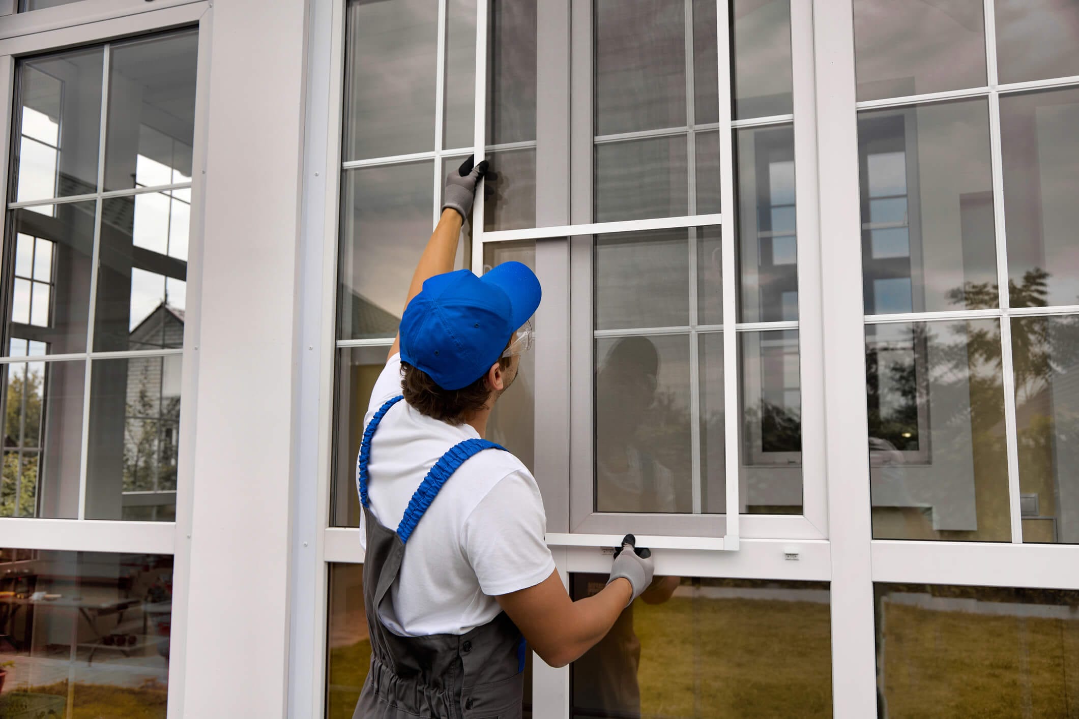 a worker putting storm windows over vinyl windows